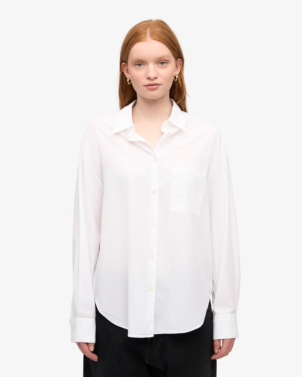 A woman with straight red hair models the Colorful Standard Organic Oversized Shirt, featuring a chest pocket, against a plain white background.