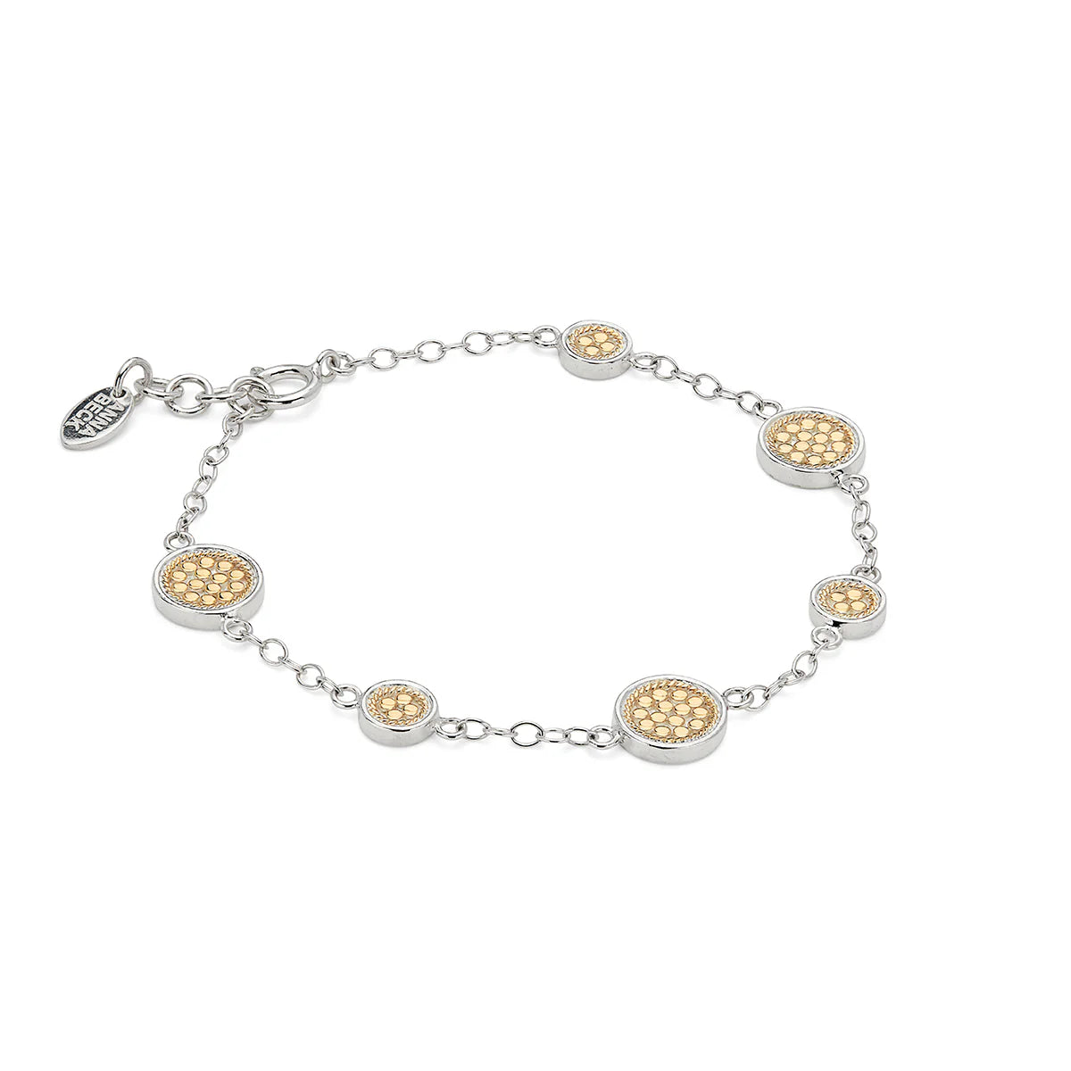 The Classic Station Bracelet - Gold & Silver by Anna Beck features sterling silver links, gold-tone accents reminiscent of gold discs, and a small charm near the clasp. This handmade bracelet adds a touch of elegance to any outfit.