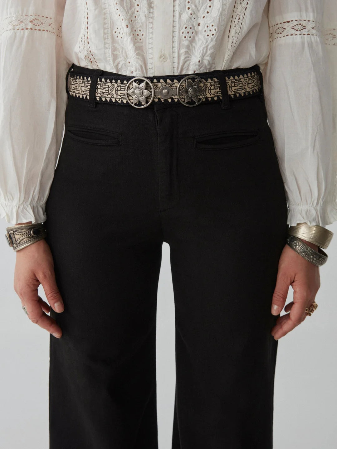 woman with blond hair wears a white embroidered blouse and long black jeans and boots maison hotel