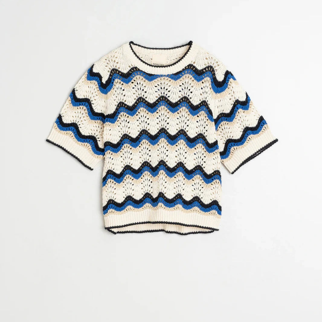 The Wavy Crochet Sweater - Blue by Indi & Cold is a short-sleeved crochet sweater with a zig-zag pattern in cream, black, and blue, shown laid flat on a white background.
