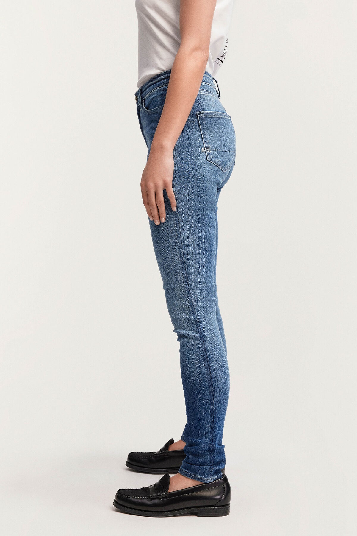 The back view of a woman wearing Denham's NEEDLE Skinny - Light Indigo denim jeans.