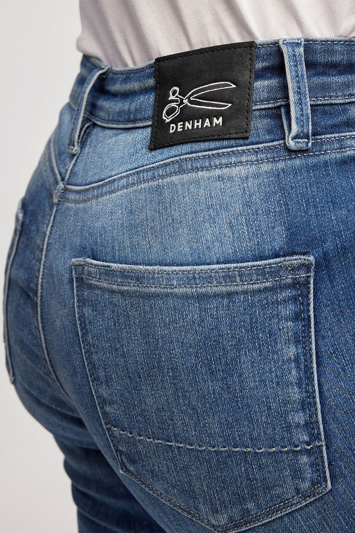 A Denham high-rise woman's jeans with the NEEDLE Skinny - Light Indigo label on the back.