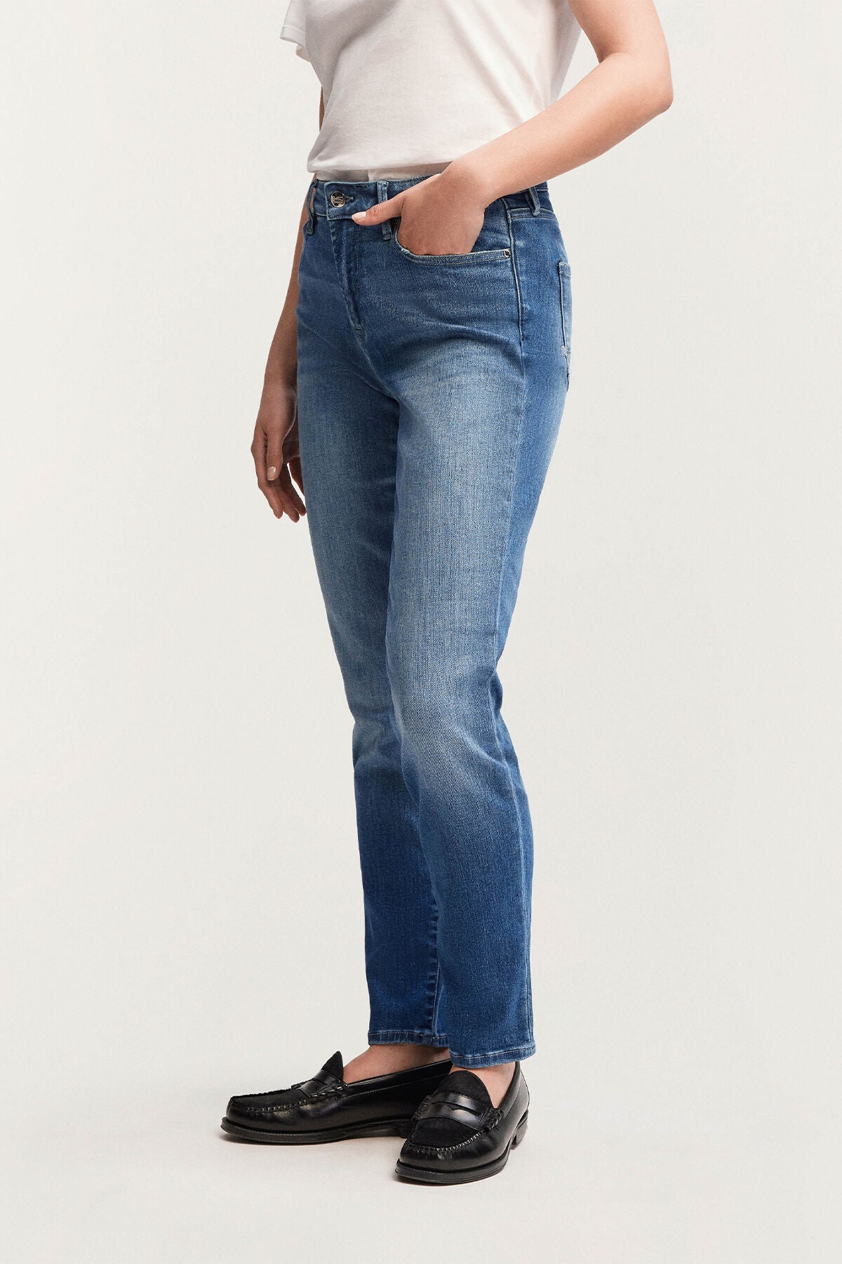A woman is standing in a Denham MARGOT High Slim - Light Worn Indigo shirt and jeans.