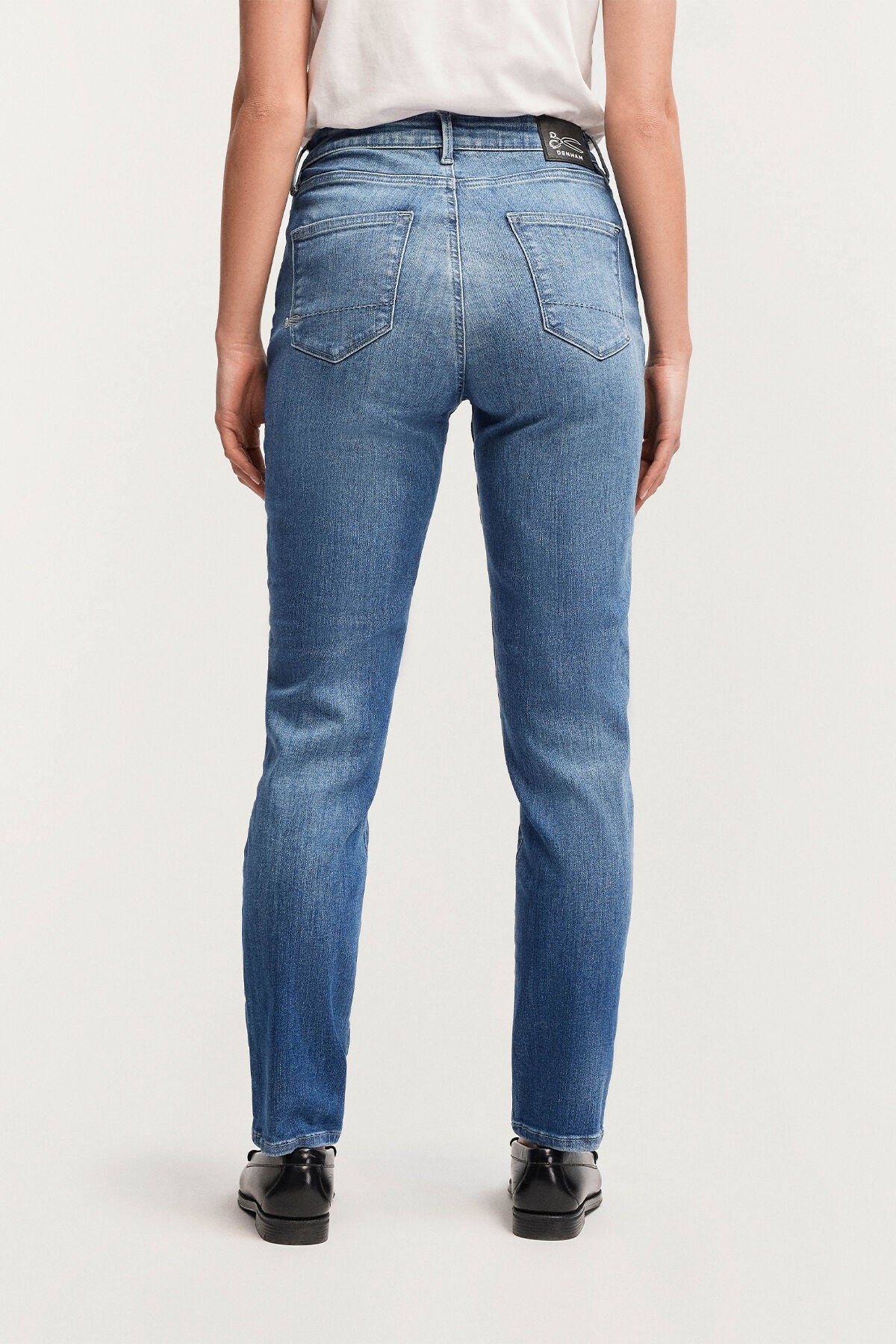 The back view of a slim woman wearing Denham's MARGOT High Slim - Light Worn Indigo blue jeans.