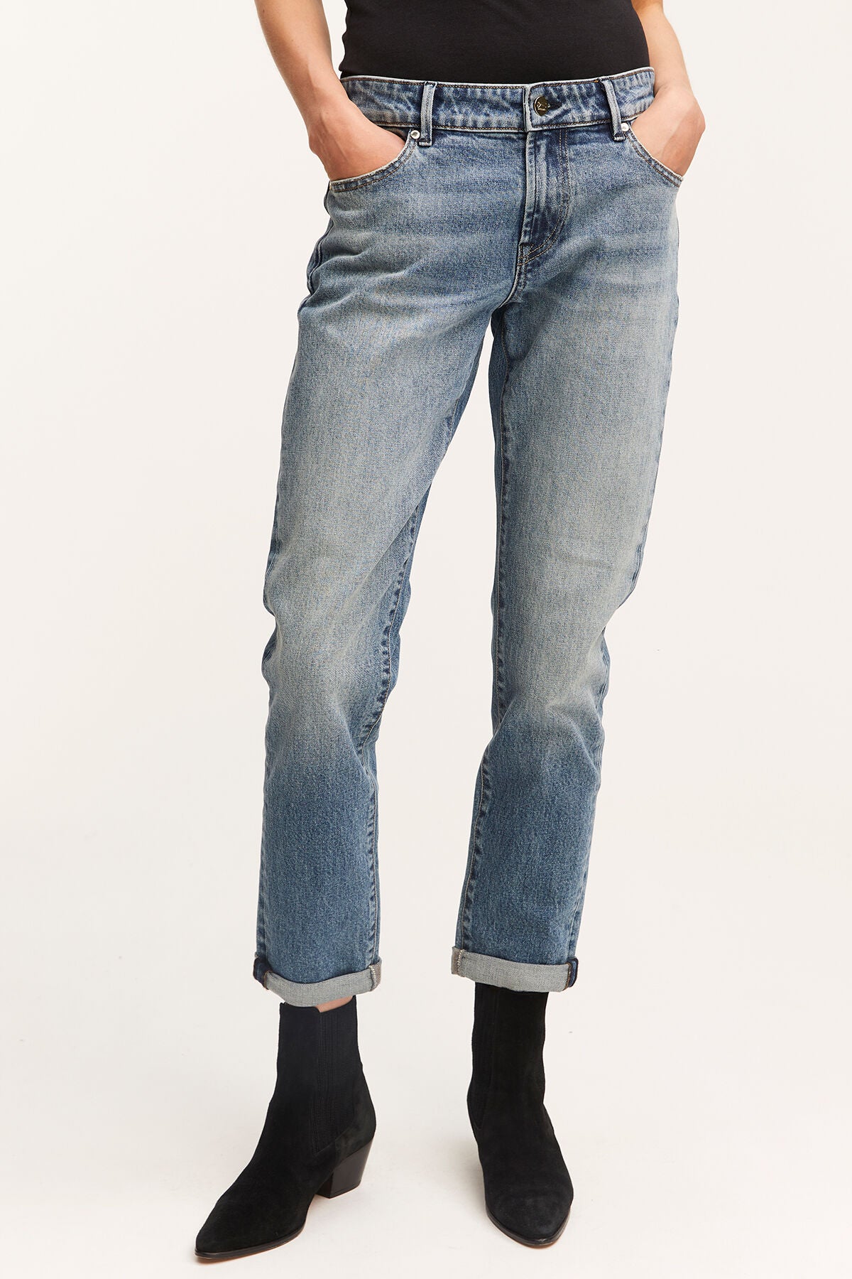 A woman wearing Denham's MONROE Girlfriend - Vintage Indigo Wash jeans with a black top.