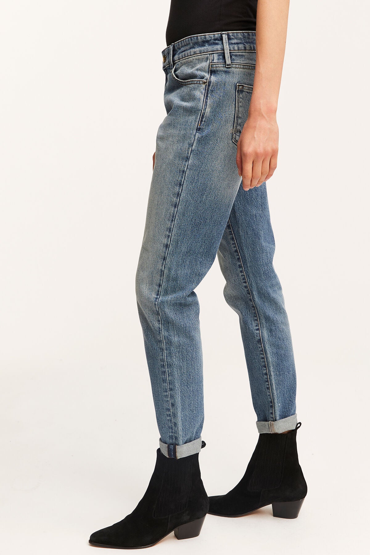 A woman wearing a pair of MONROE Girlfriend - Vintage Indigo Wash jeans made from organic cotton and Denham black boots.
