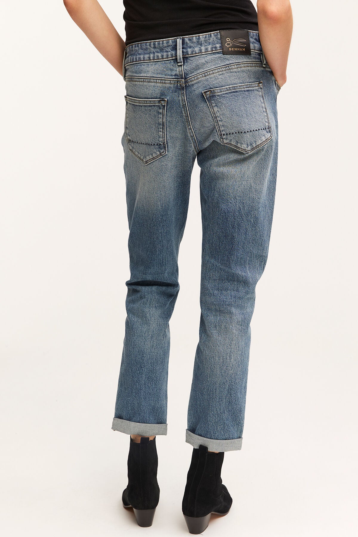 The back view of a woman wearing a pair of MONROE Girlfriend - Vintage Indigo Wash jeans made from GOTS-certified organic cotton with a vintage inspired wash by Denham.