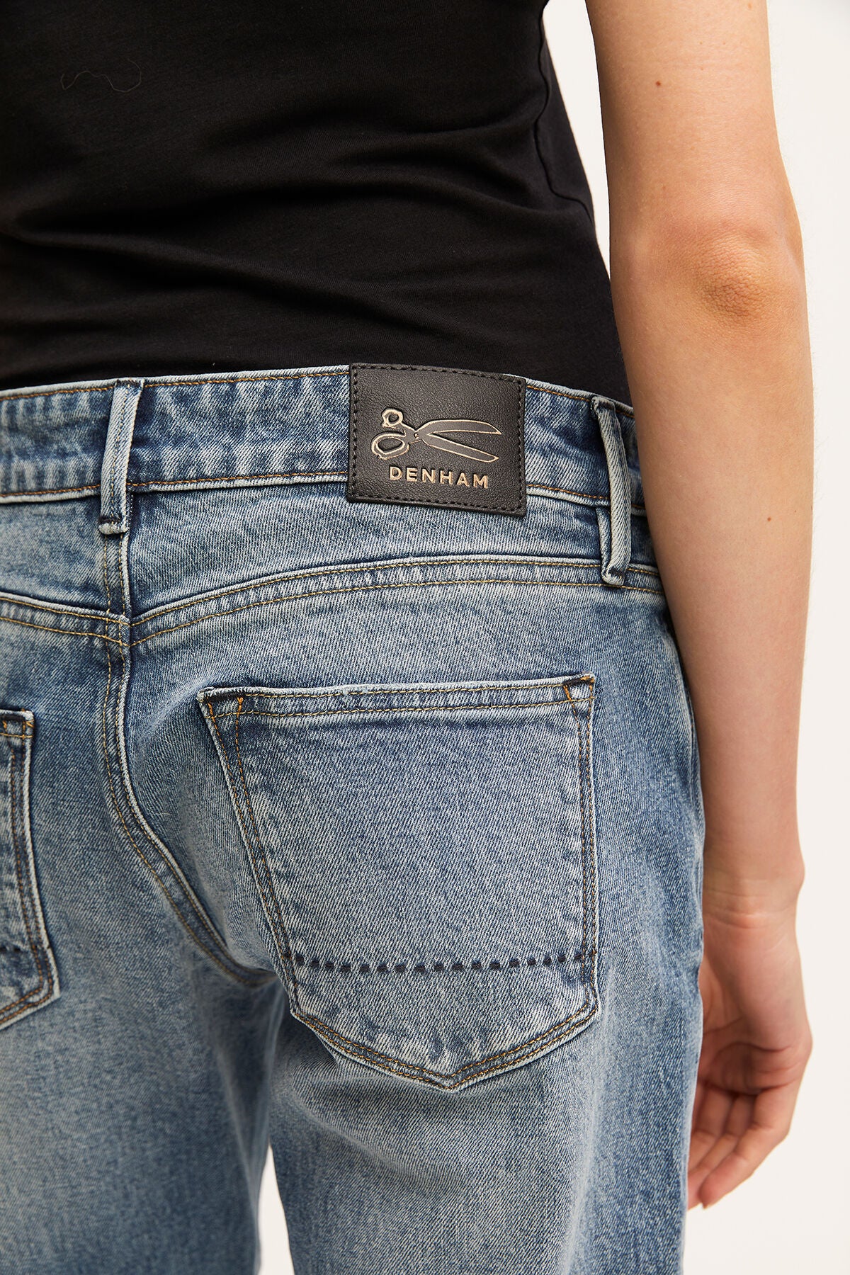 The back of a woman's MONROE Girlfriend - Vintage Indigo Wash jeans with a GOTS-certified label on the organic cotton fabric by Denham.