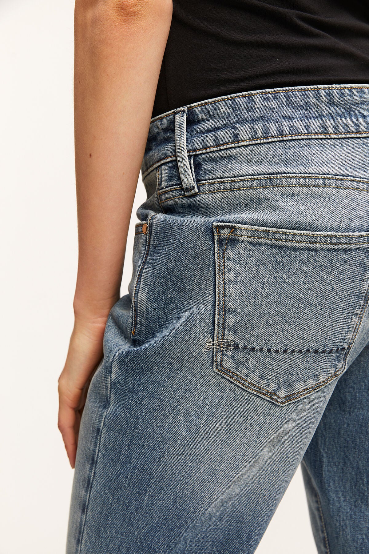 The back view of a woman's MONROE Girlfriend jeans by Denham, featuring an organic cotton fabric and a vintage inspired wash. These jeans are GOTS-certified, ensuring their sustainability and eco-friendliness.
