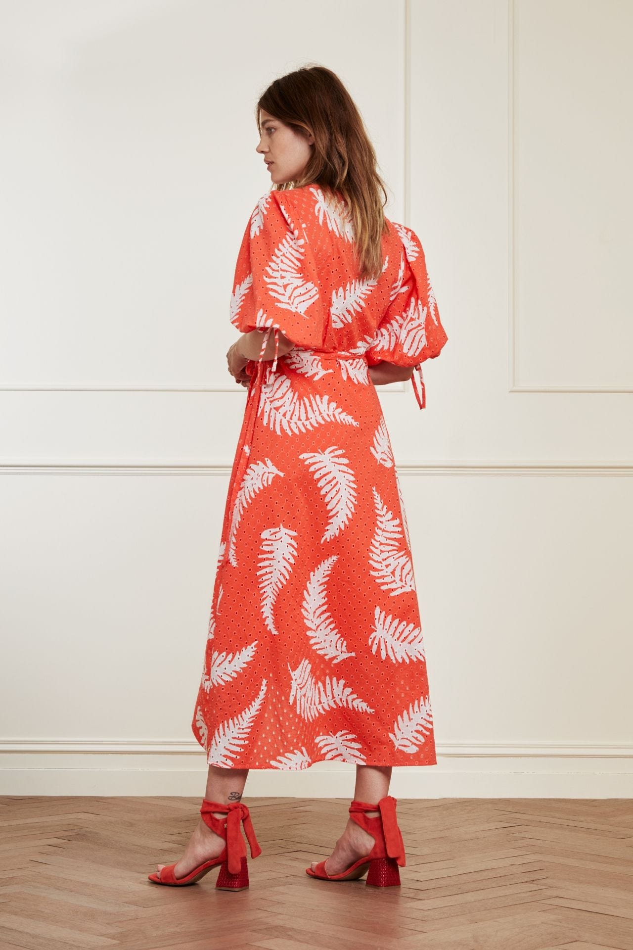 The back view of a woman in a Fabienne Chapot Charlie Broderie Dress - Hot Coral feminine wrap dress.