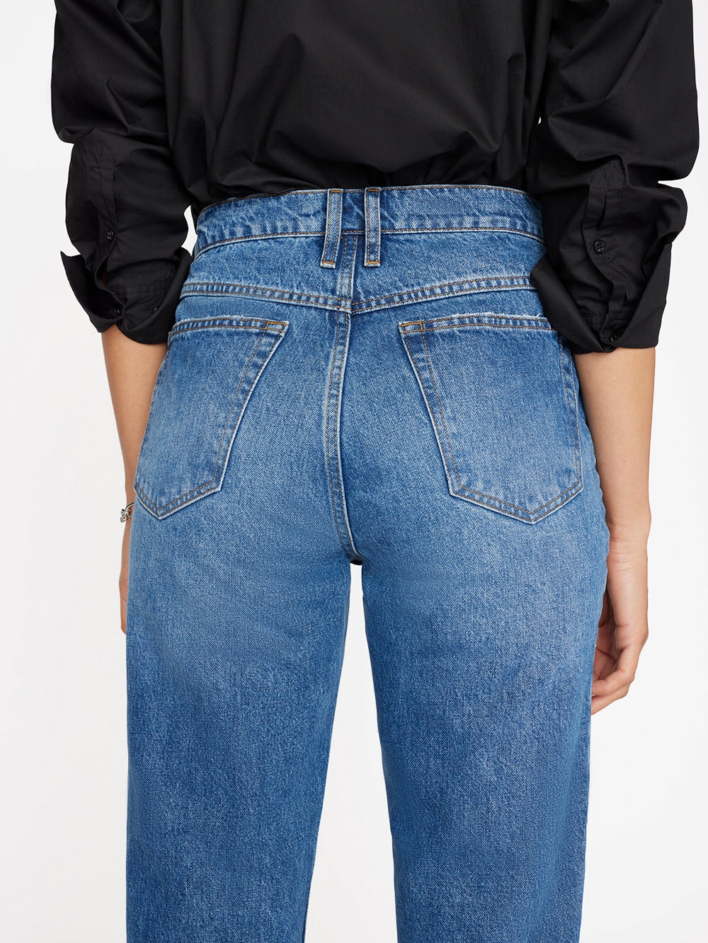 The back view of a woman in Le High 'N' Tight Taper - Stearnlee denim jeans by Frame.