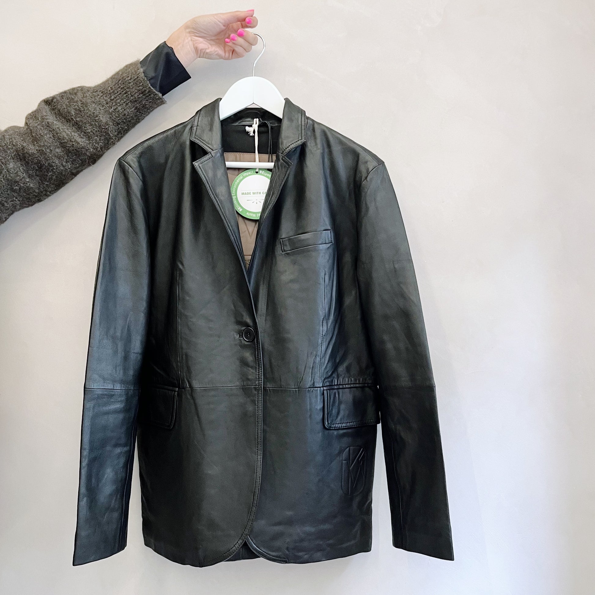 A MDK Celaya Classic Blazer - Black lambskin leather jacket hanging on a hanger.
