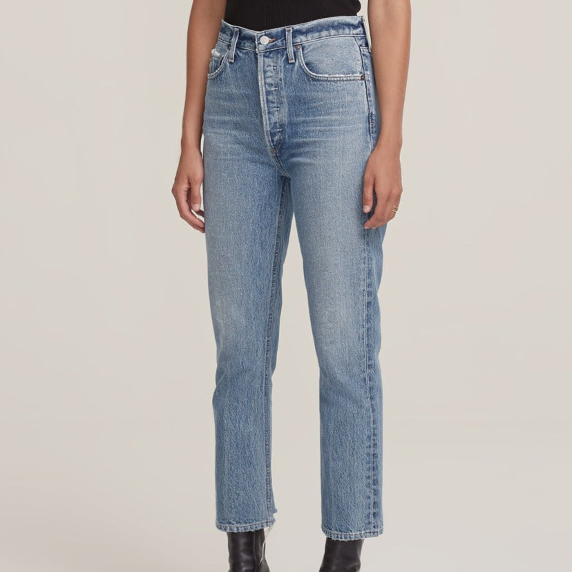 A woman wearing a pair of AGOLDE Riley Straight Crop - Emulsion high waisted jeans made from organic cotton denim and a black top.