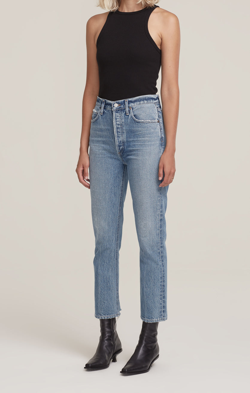 Riley, a woman wearing AGOLDE's Riley Straight Crop - Emulsion high waisted jeans and a black tank top.