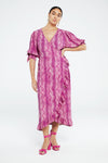 person wears Fabienne Chapot Channa dress in snake print styles with pink hig heeled sandals, against a white backdrop