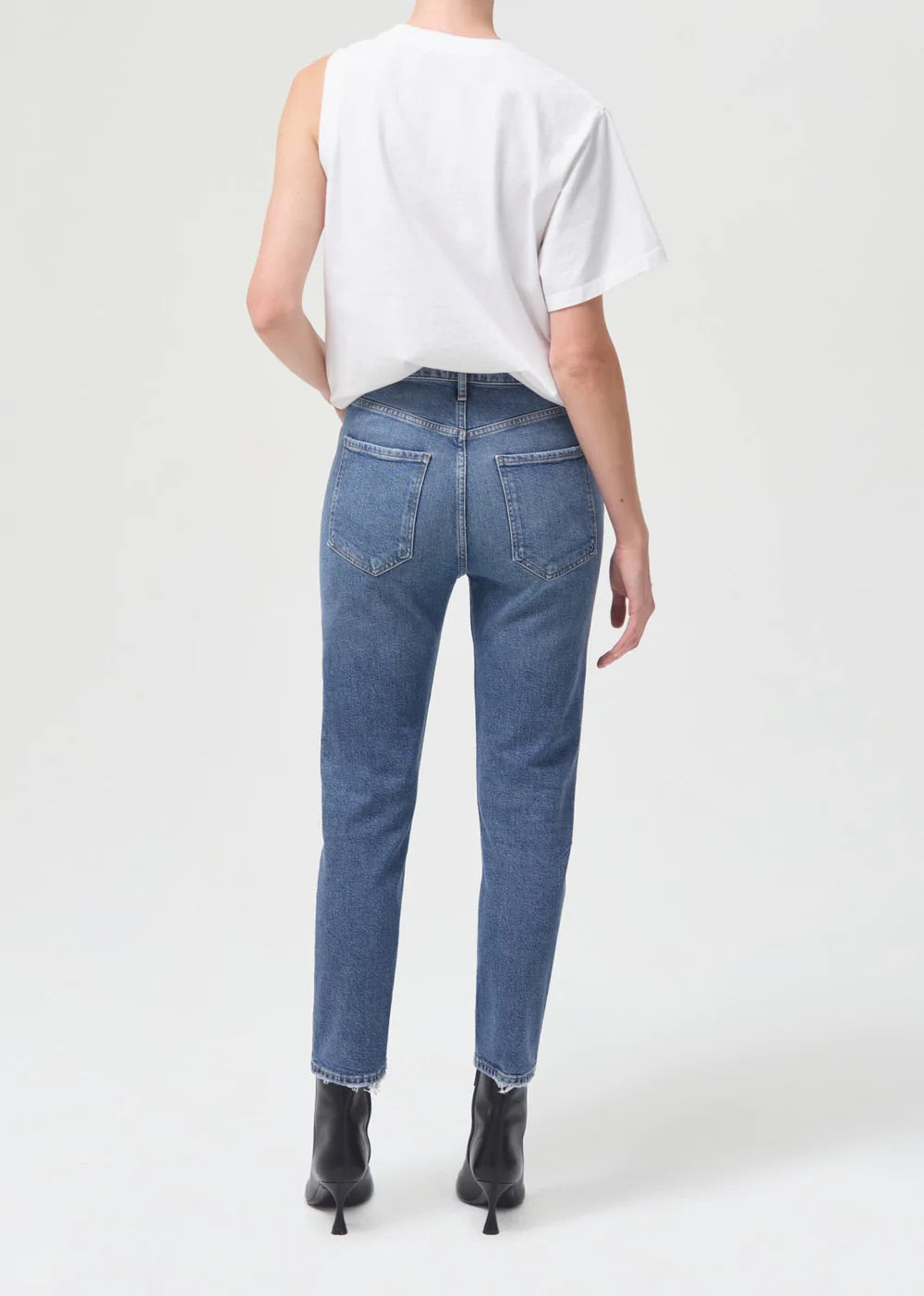 The back view of a woman wearing a white t-shirt and high-rise jeans, including the Riley Straight Crop - Silence by AGOLDE.