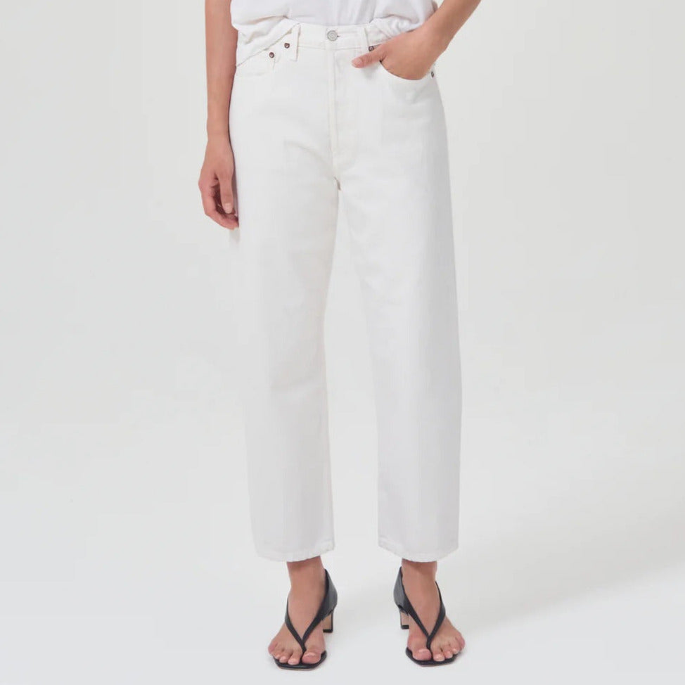 lower body wears white straight leg agolde jeans with black sandals against a white studio backdrop