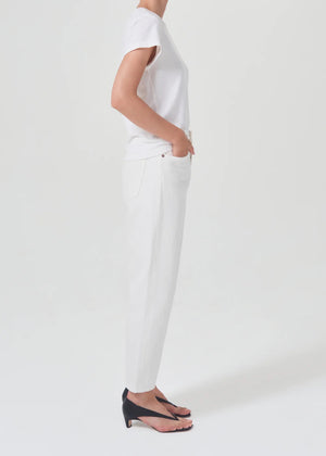 person wears white straight leg agolde jeans with black sandals showing the side view against a white studio backdrop
