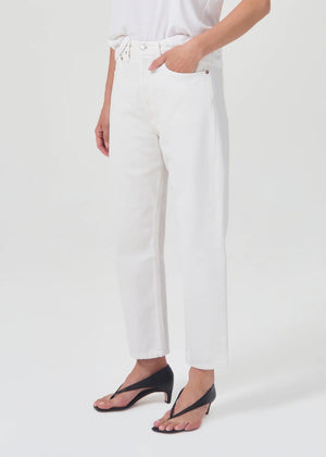 lower body wears white straight leg agolde jeans with black sandals against a white studio backdrop