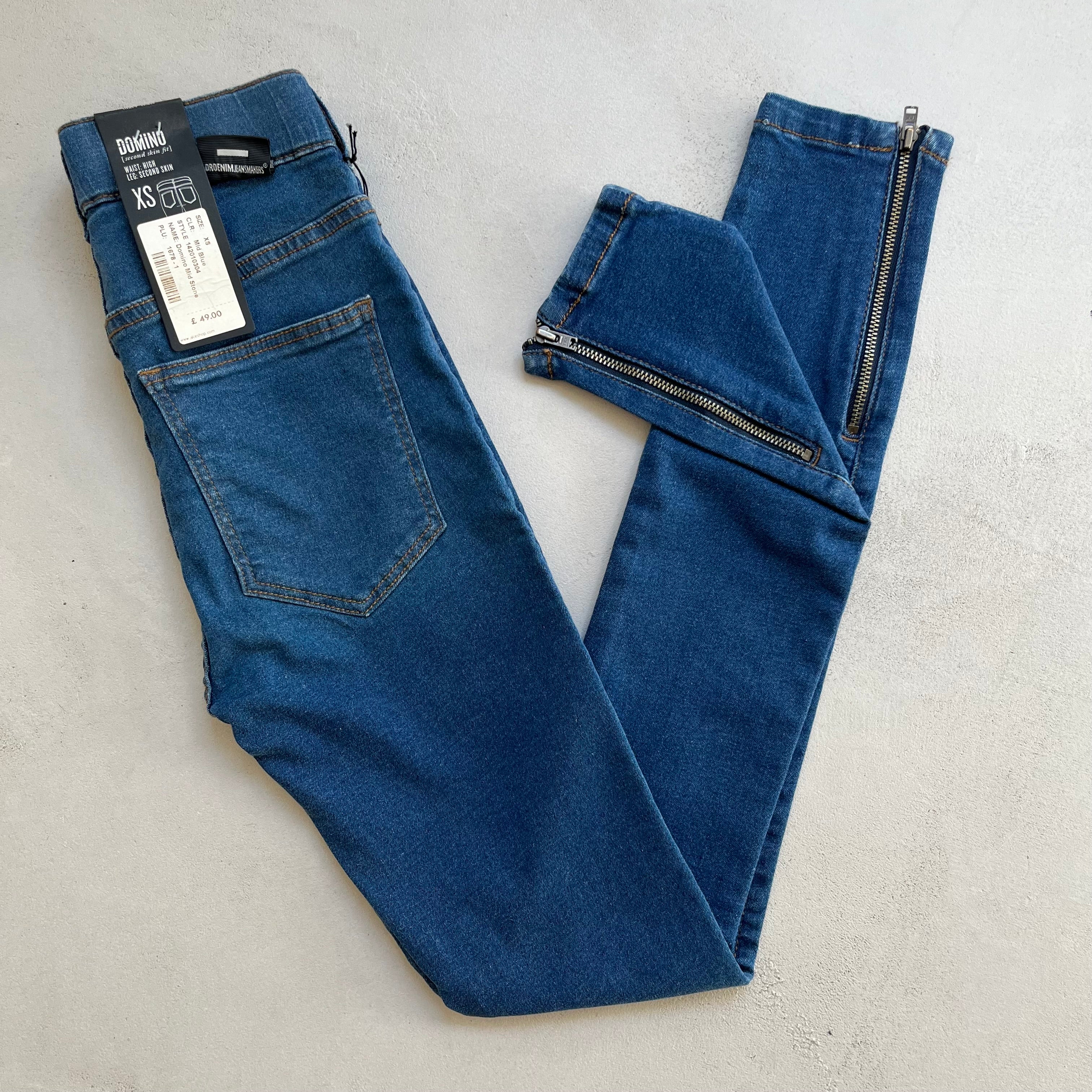 A pair of Dr Denim Domino Ankle Zip - Stone Blue high-rise skinny blue jeans with a zipper on the side, made of denim.