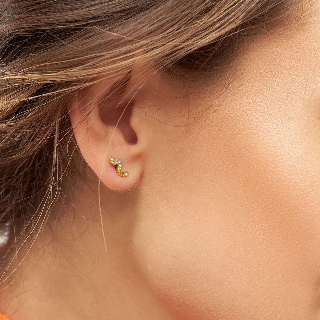 A woman's ear with a Lulu Copenhagen Snaky Gold - Rainbow stud earring.