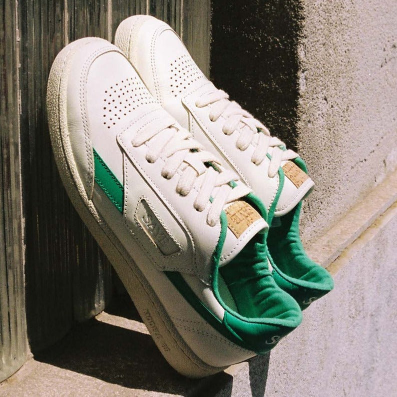 A pair of SAYE Modelo '89 Sneakers - Green leaning against a wall.