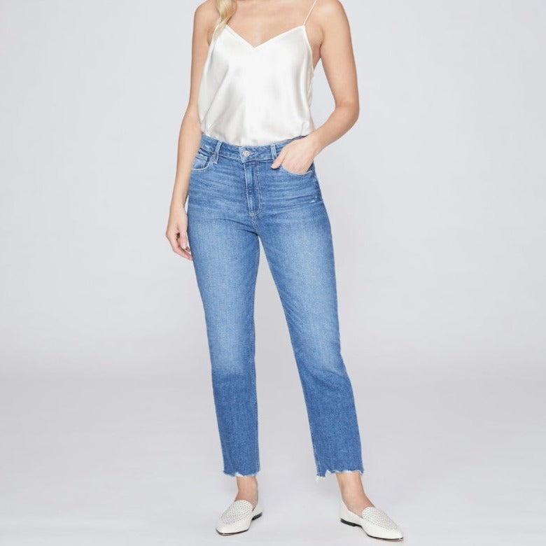 An elegant model showcasing a Paige Sarah Straight Crop - Love Letter Distressed high-waisted denim look with a white tank top and flared jeans.