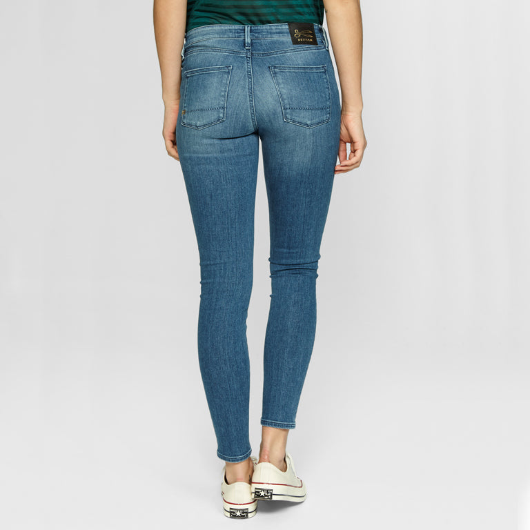 The back view of a woman wearing SPRAY Skinny - Golden Rivet Prosecco jeans by Denham and a green t-shirt, showcasing both comfort and stretch.