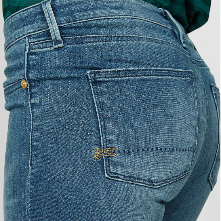 The back pocket of Denham's SPRAY Skinny - Golden Rivet Prosecco jeans, featuring a mid-blue hue for a stylish look, and offering comfort and stretch.
