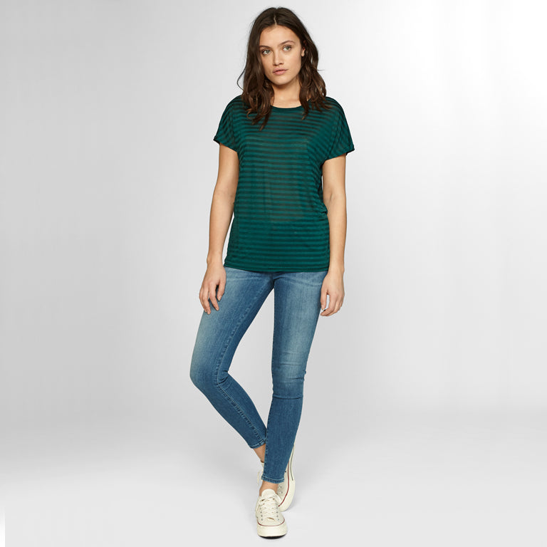 A woman wearing a Denham green striped t-shirt and Denham skinny fit jeans.