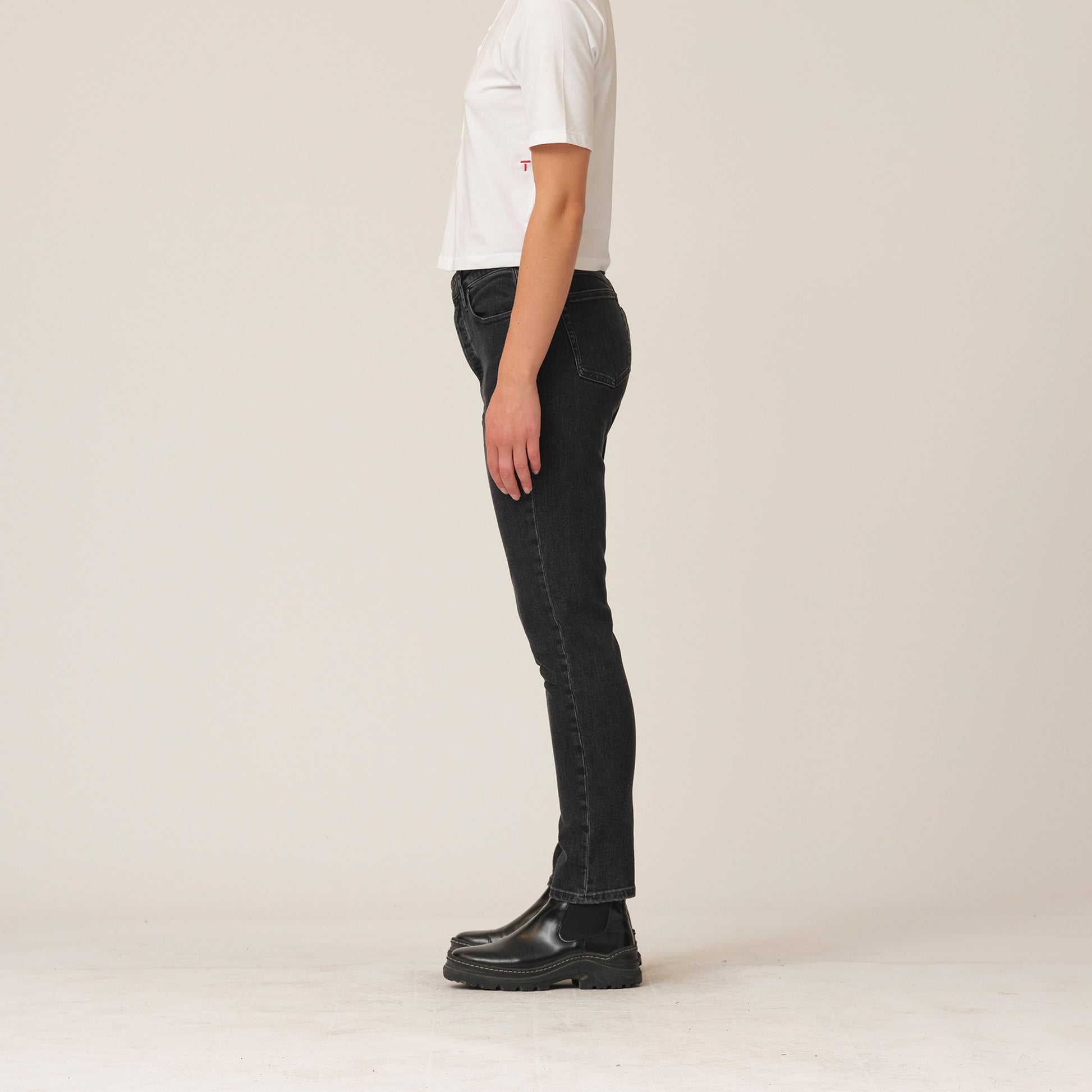 A woman wearing Tomorrow Denim's Hepburn Slim Jeans - Original Black made from organic cotton denim fabric and a white t-shirt.