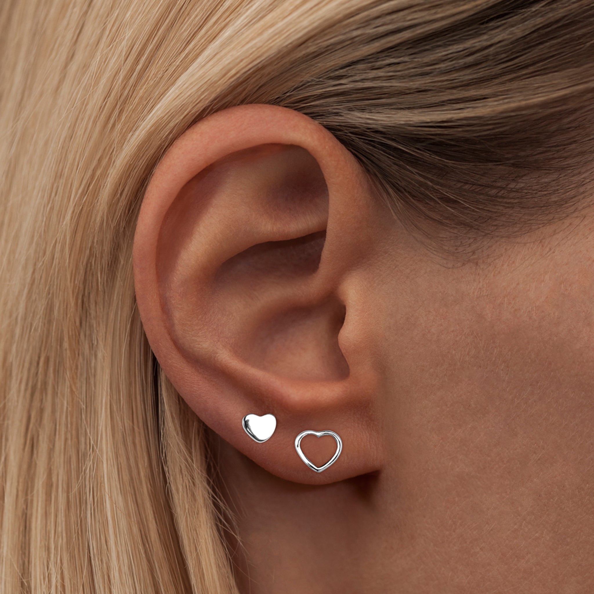 A woman's ear with a shiny Lulu Copenhagen Family Love Earring Pair - Silver.