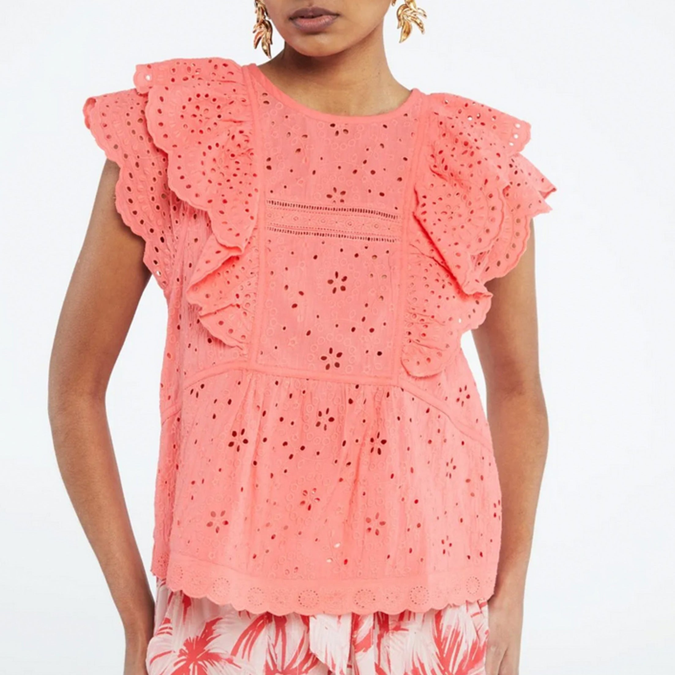 The model is wearing the Gigi Top - Pink Papaya, a regular fitting coral top made of organic cotton with ruffled ruffles by Fabienne Chapot.