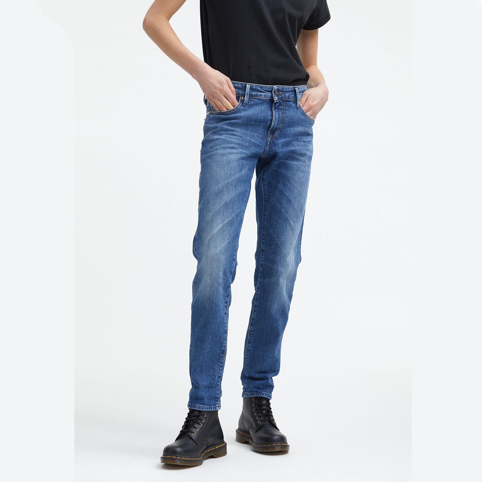 A woman wearing Denham's MONROE Mid Girlfriend - Light Fade & Whiskers Jeans, paired with a black t-shirt.