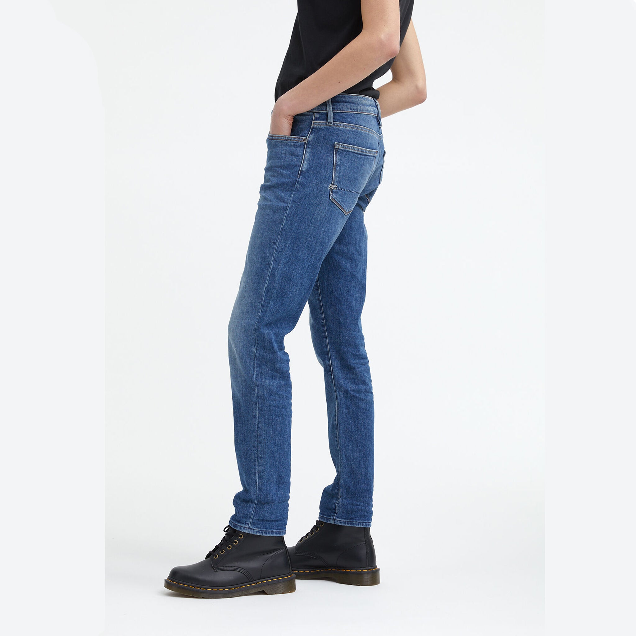 A woman wearing Denham's MONROE Mid Girlfriend - Light Fade & Whiskers jeans and a black t-shirt.