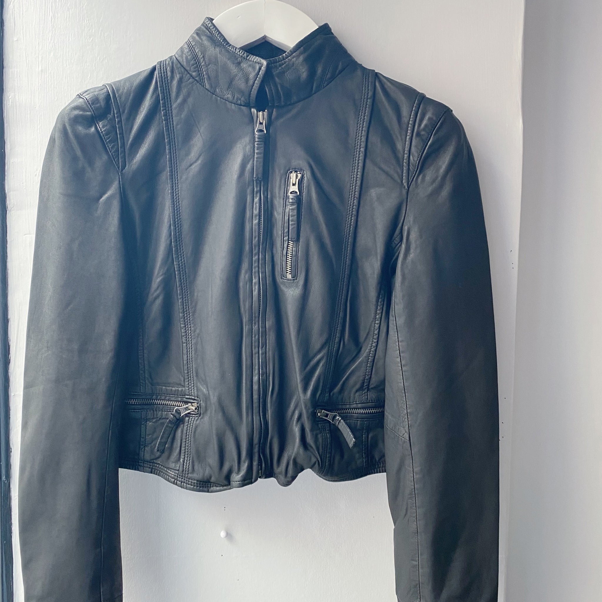 Description: A MDK Leather Rucy Jacket - Black zipped on a wall.