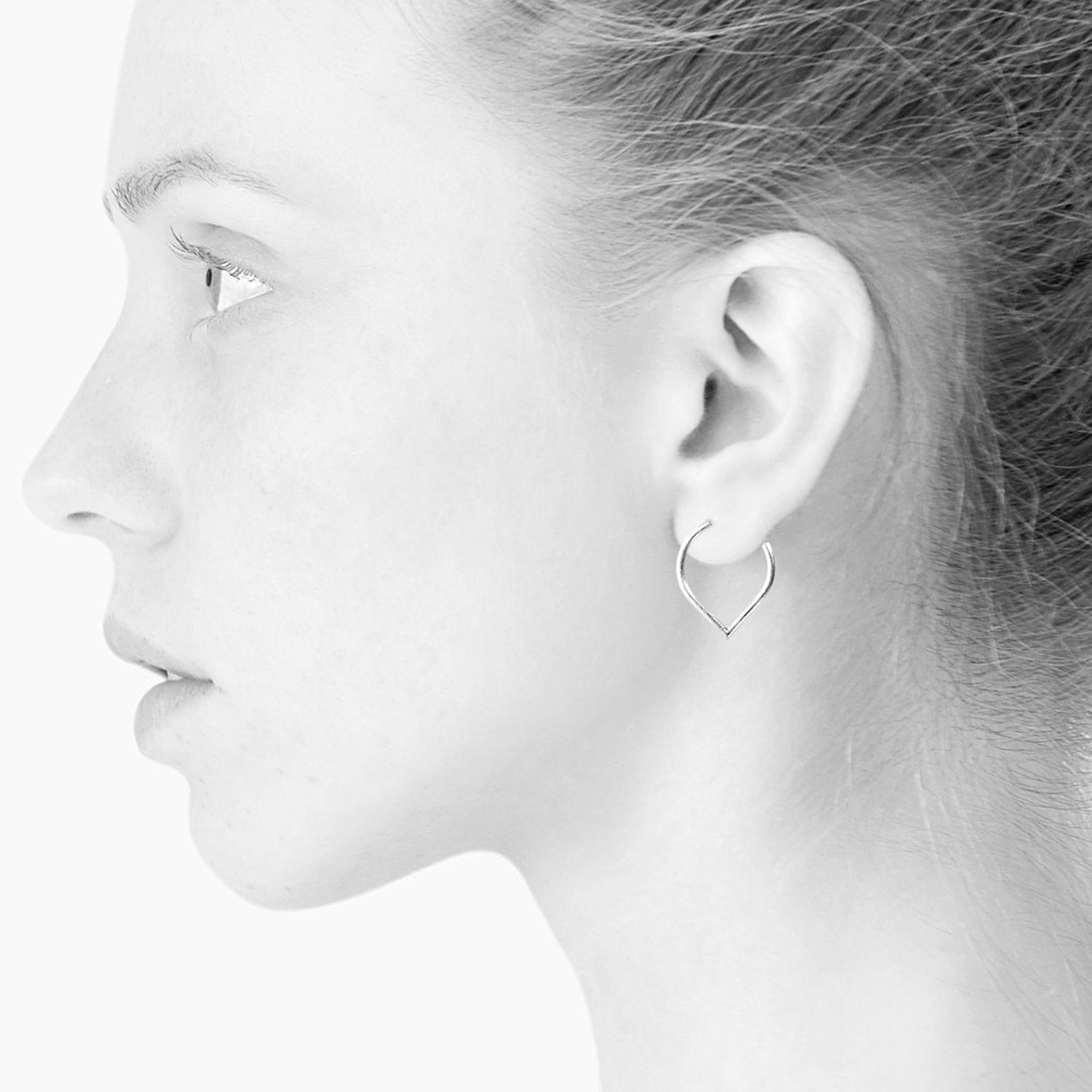 A woman wearing a pair of Scherning Lee Teardrop Hoops - Silver earrings.