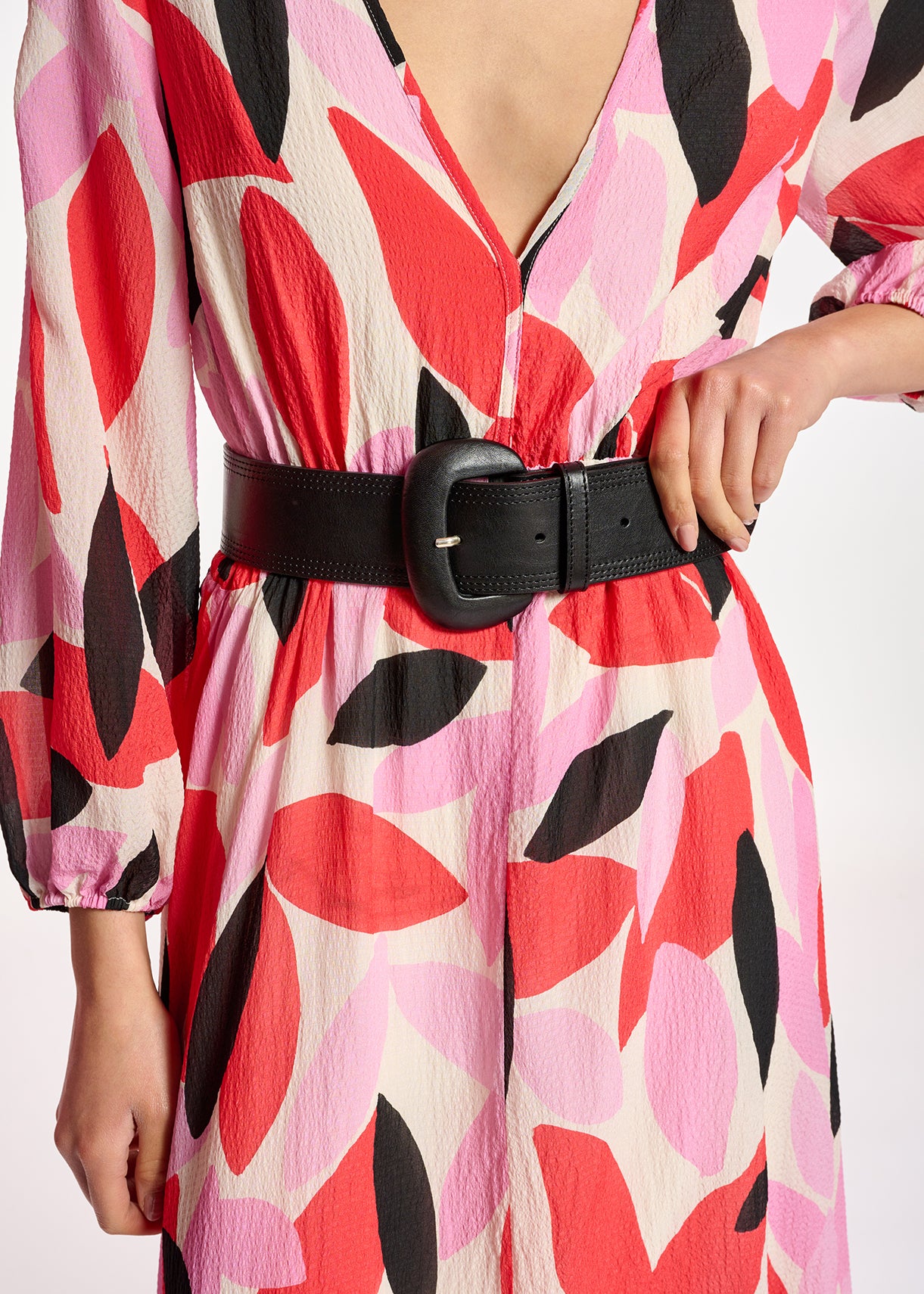 A woman wearing a luxurious Essentiel Antwerp Crab Puff Sleeve Dress - Multi with a belt, adorned in pink and black floral print.