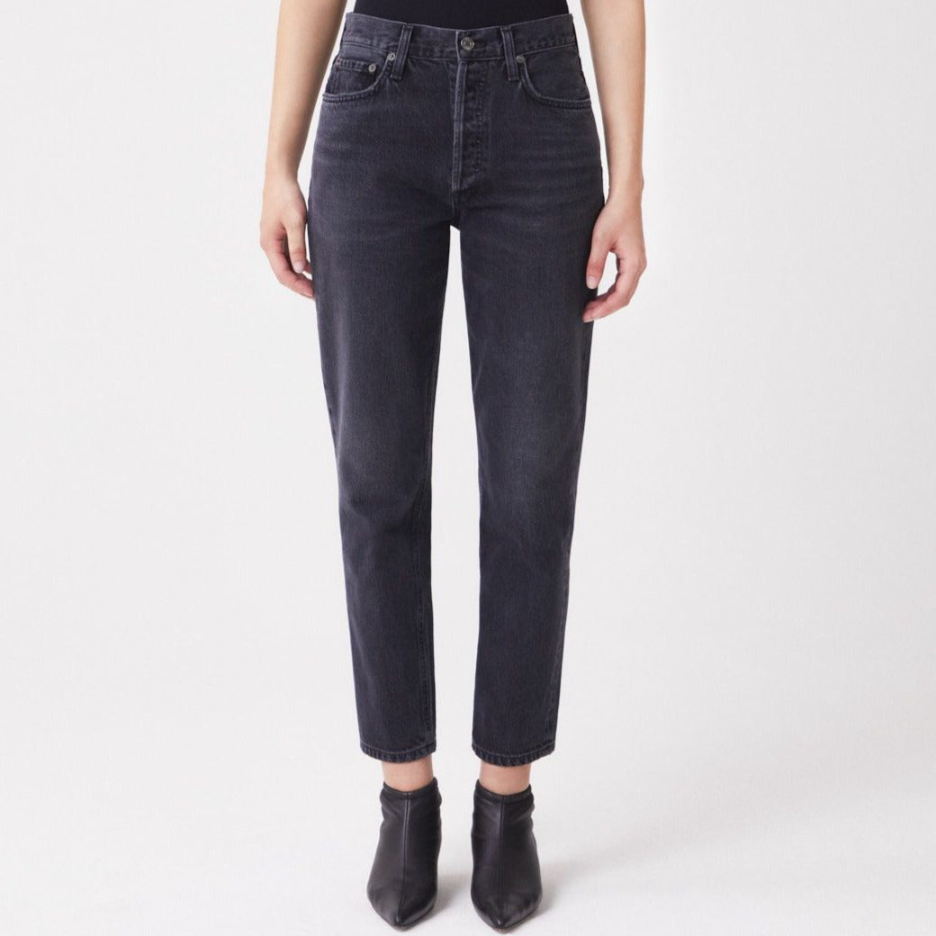 A woman wearing the AGOLDE Fen Straight - Shambles black jeans and a black top made from organic cotton.