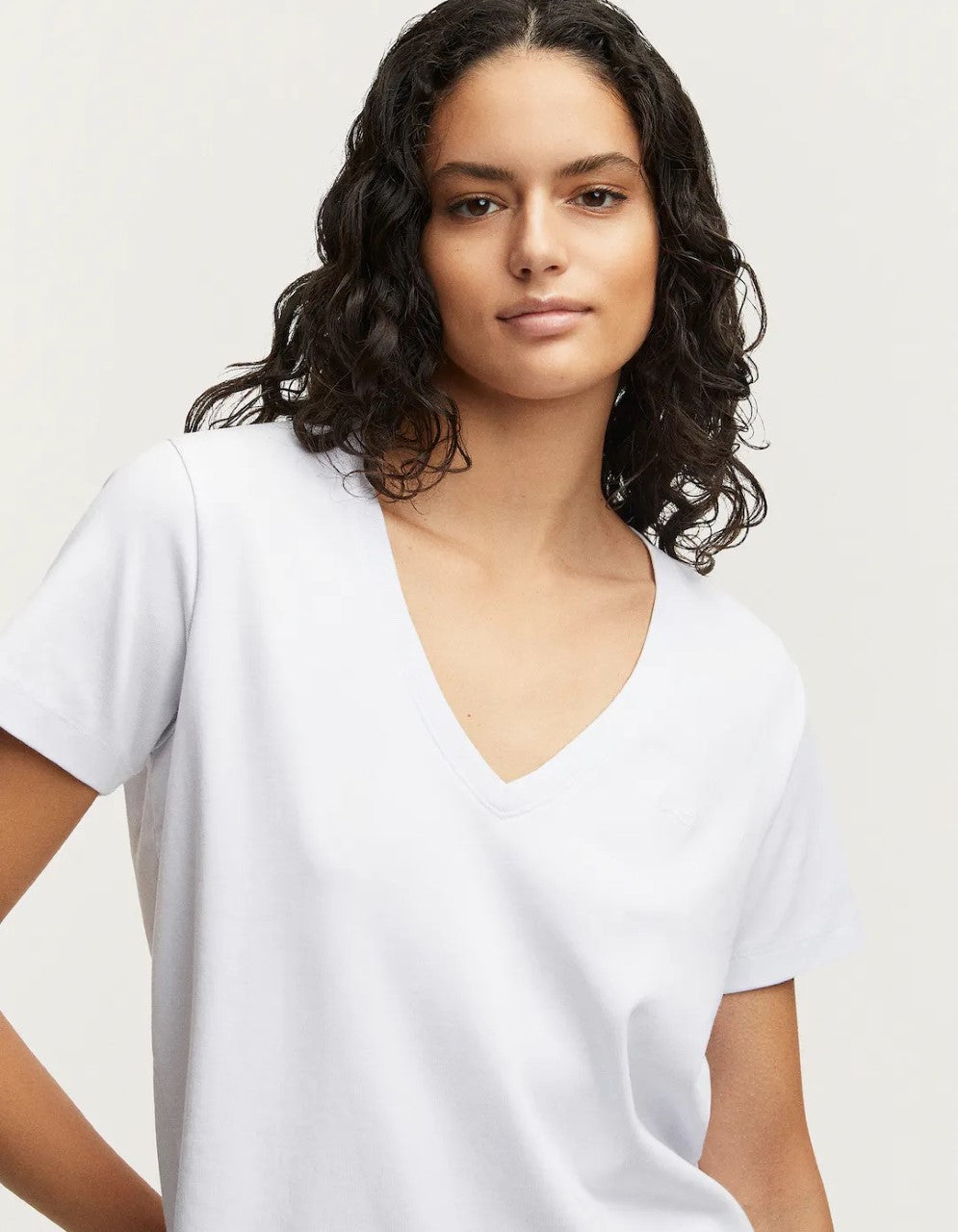 person wears the denham white ramona v-neck tee against a grey studio background showing the front of the Tee. 